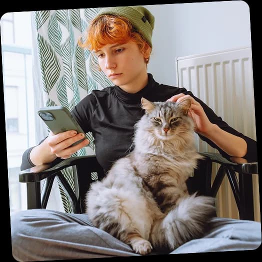 An ambassador reading on her phone with a long-haired cat on her lap